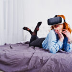 Red haired girl in bed with vr glasses at studio room.